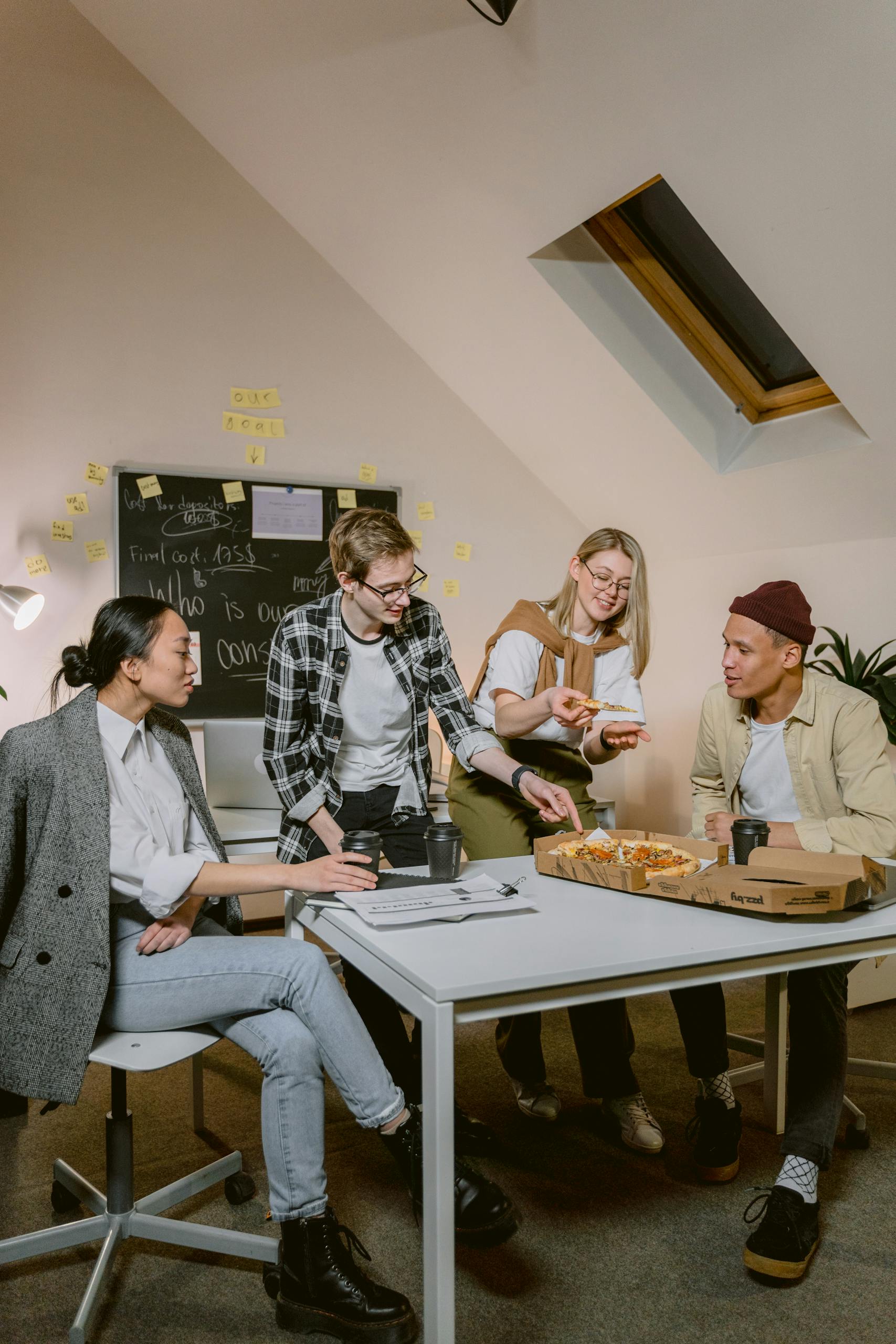 A group of diverse young professionals sharing pizza during a break in a modern office environment.